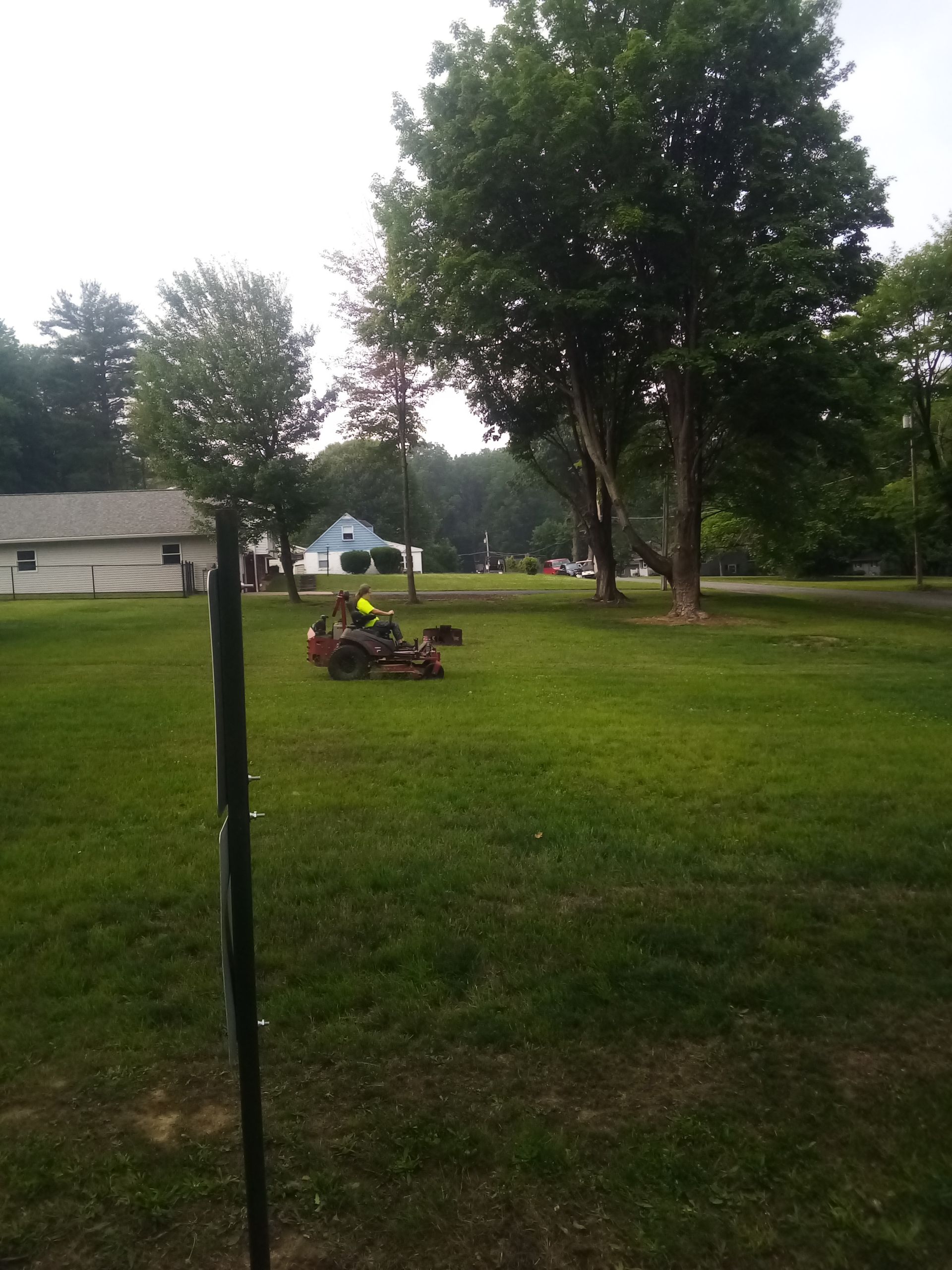 A person is riding a lawn mower in the middle of a lush green field.