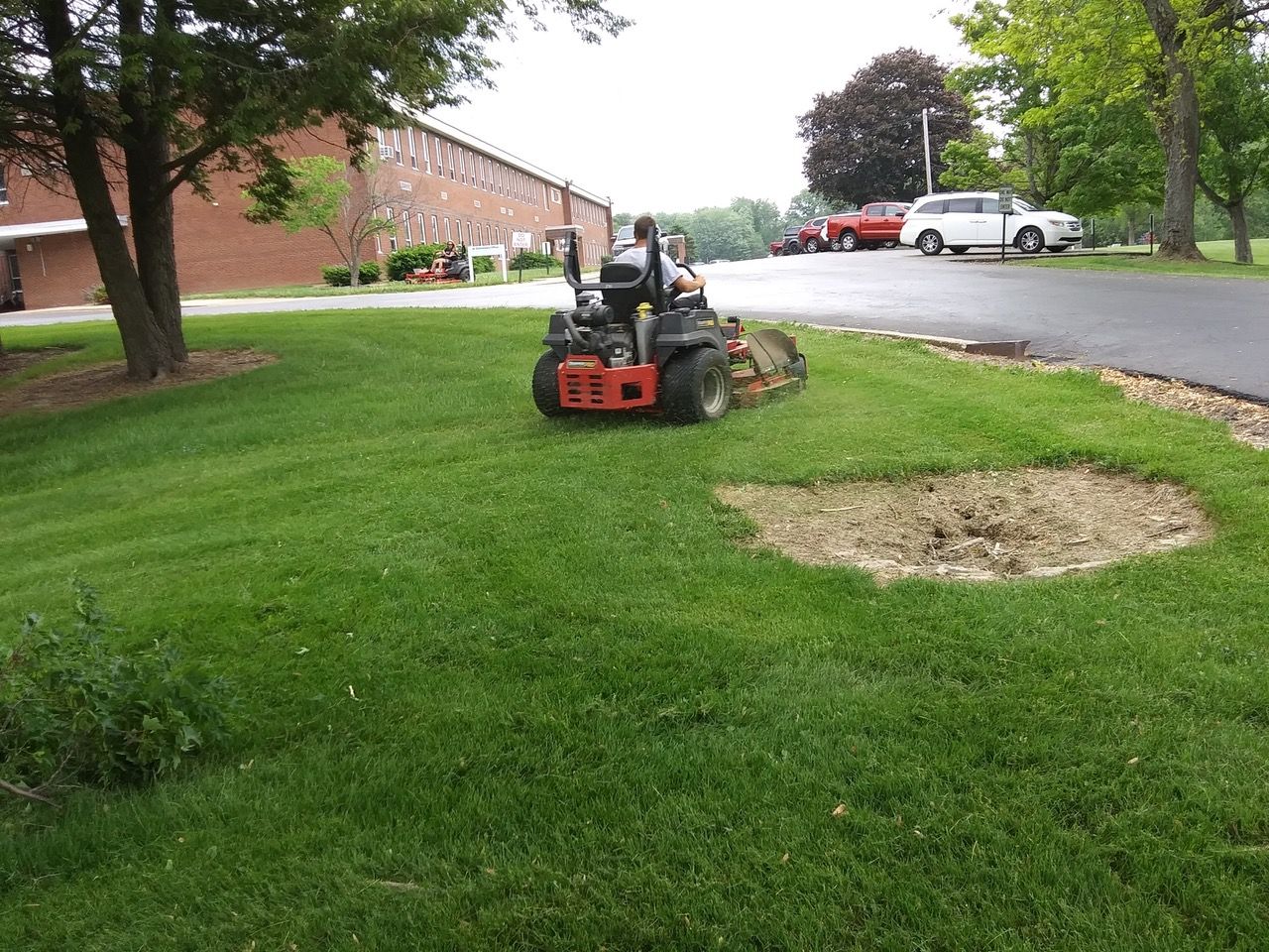 A person is riding a lawn mower on a lush green lawn