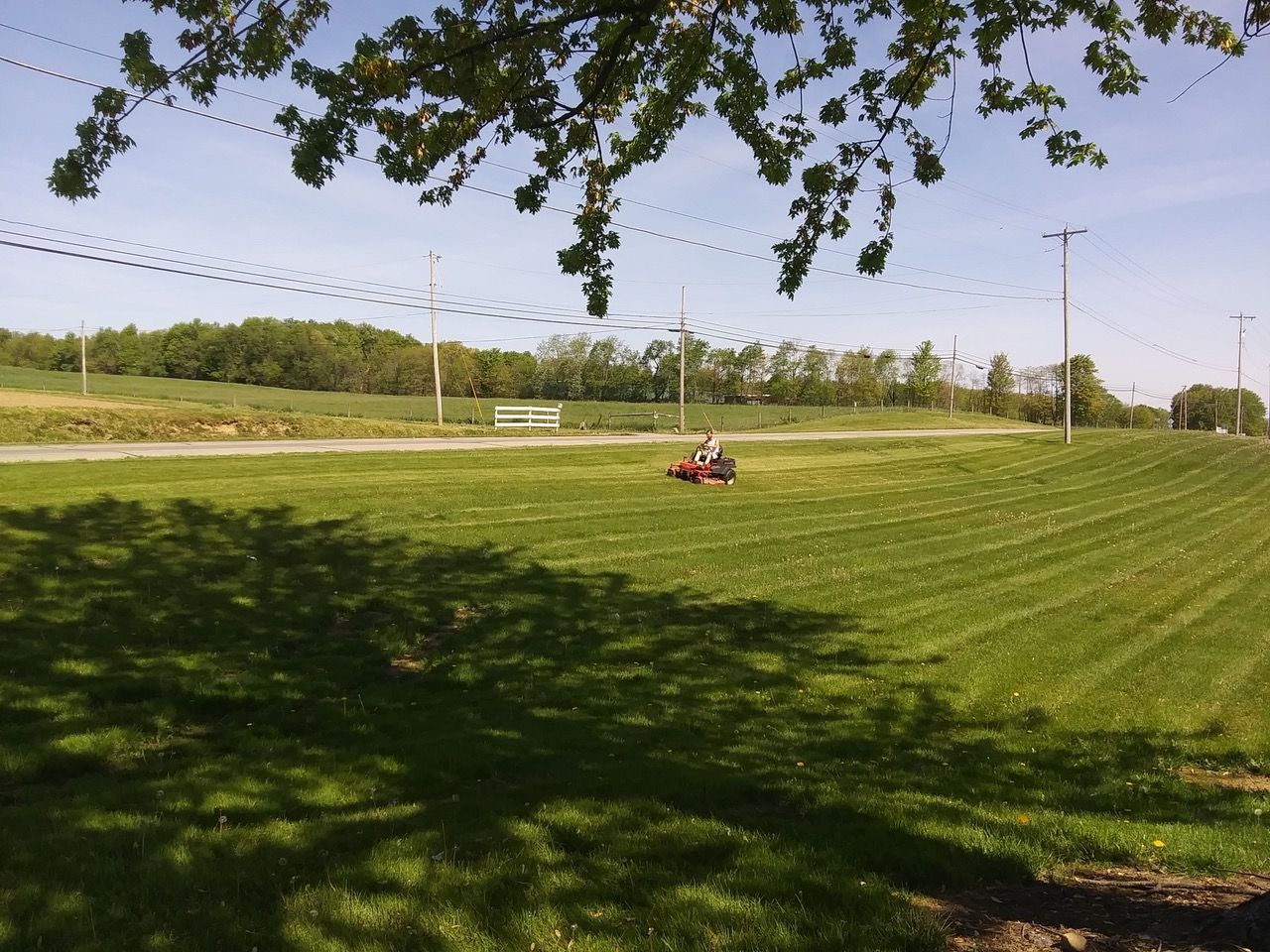 A person is mowing a lush green field with a lawn mower