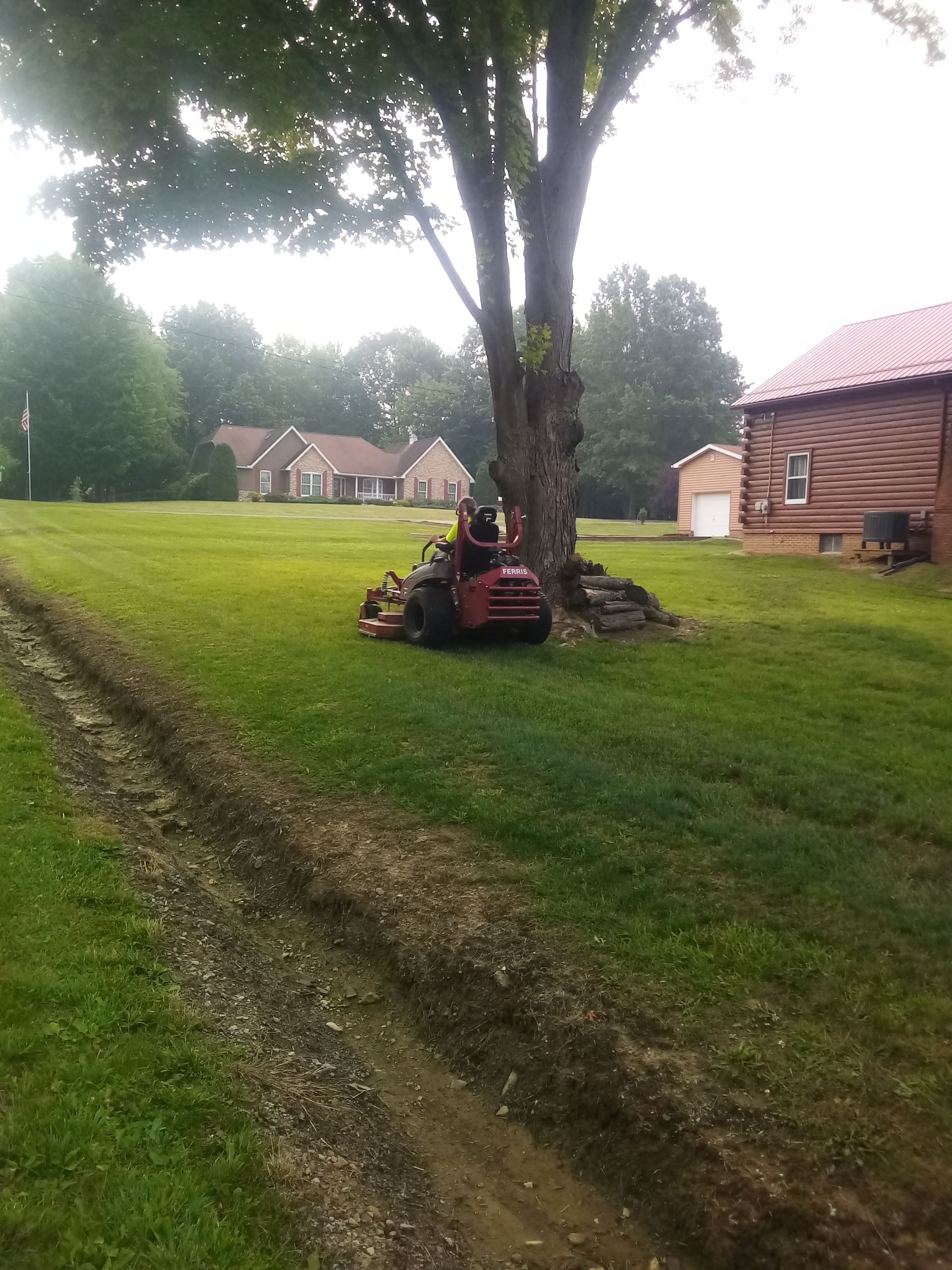 A person is riding a lawn mower in a lush green field.
