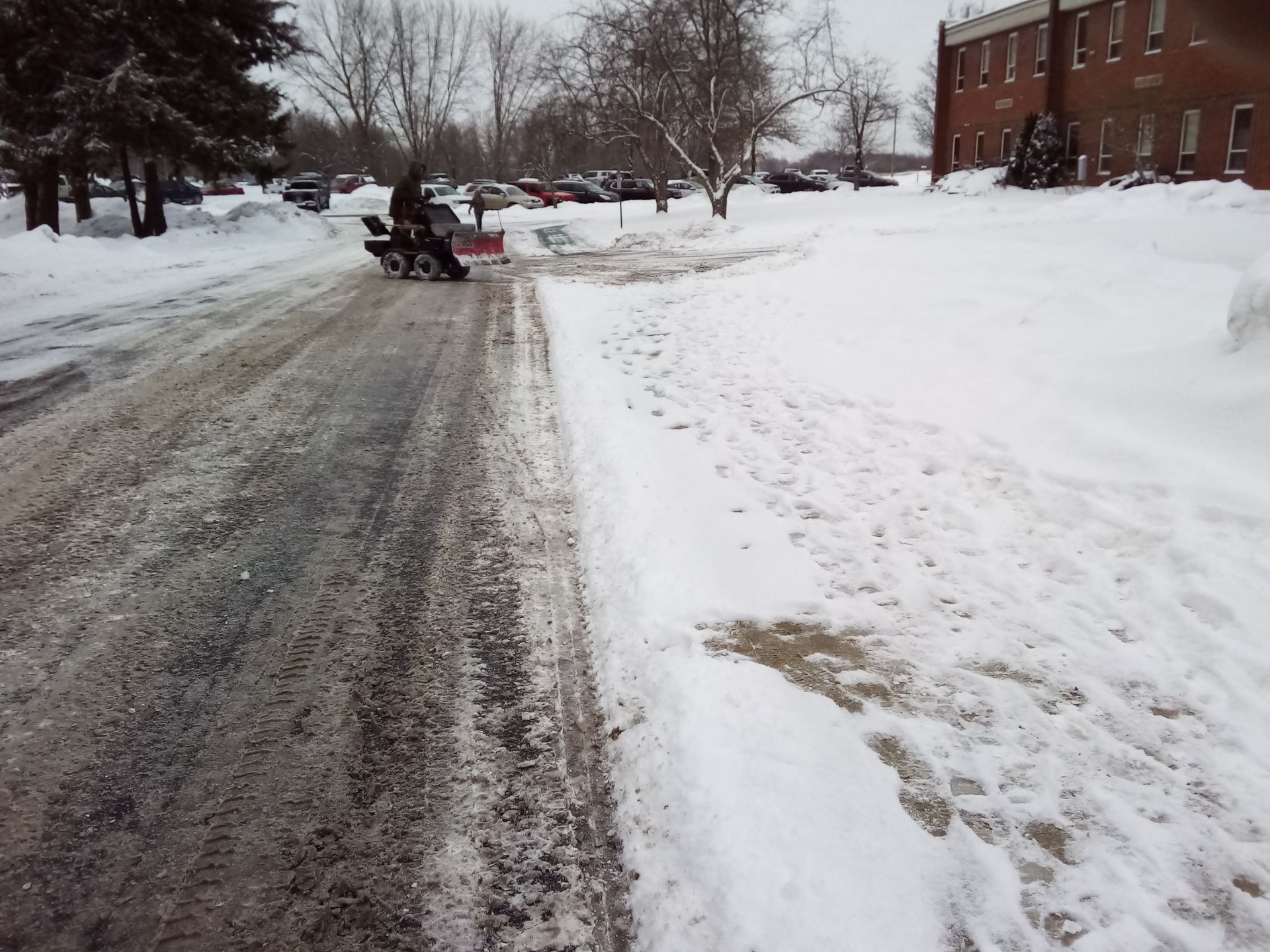 A snow plow is clearing snow from the side of the road