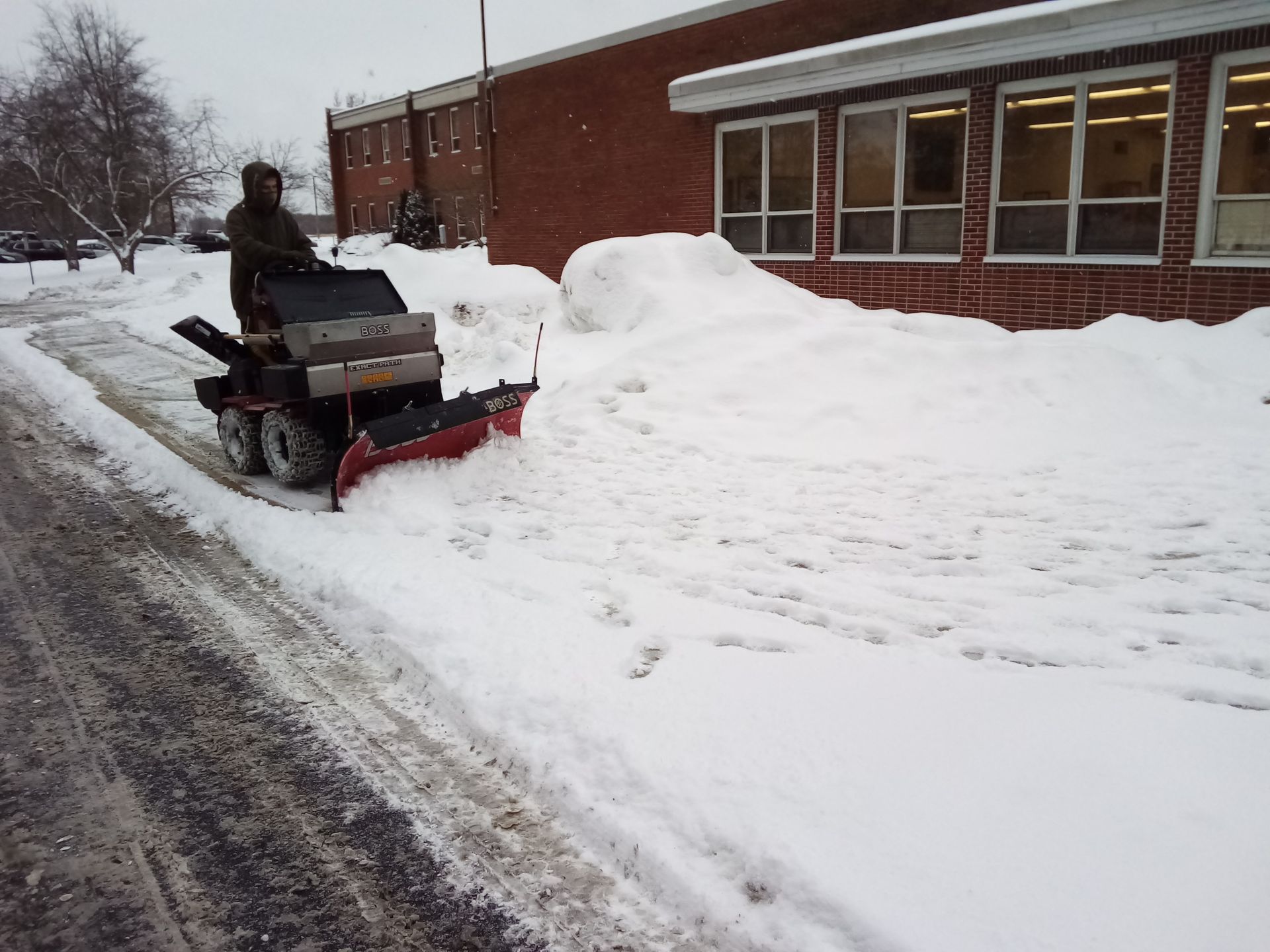 A man is plowing snow on the side of the road