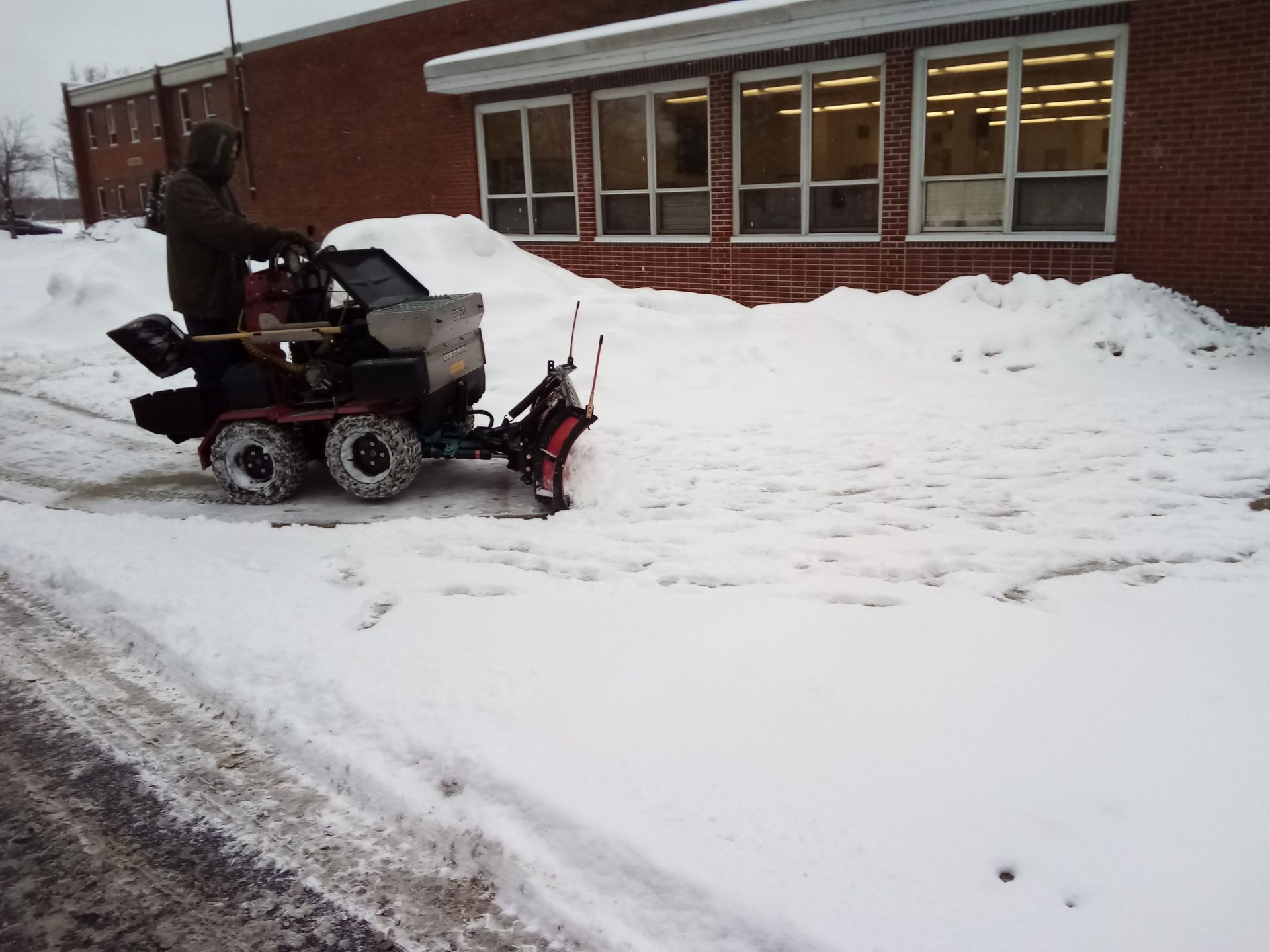 A man is driving a snow plow in the snow