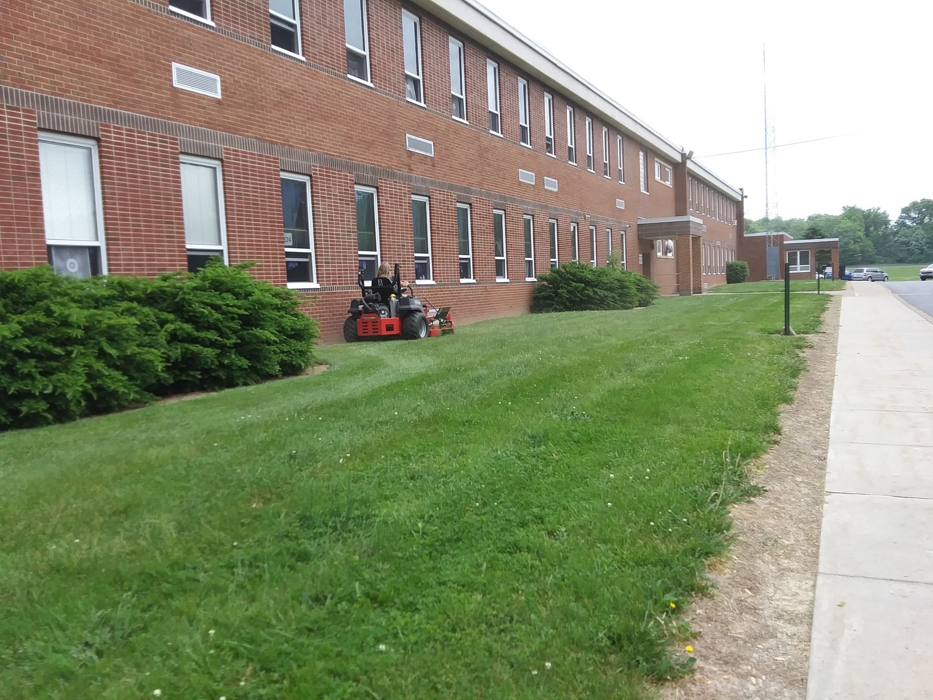 A lawn mower is parked in front of a large brick building