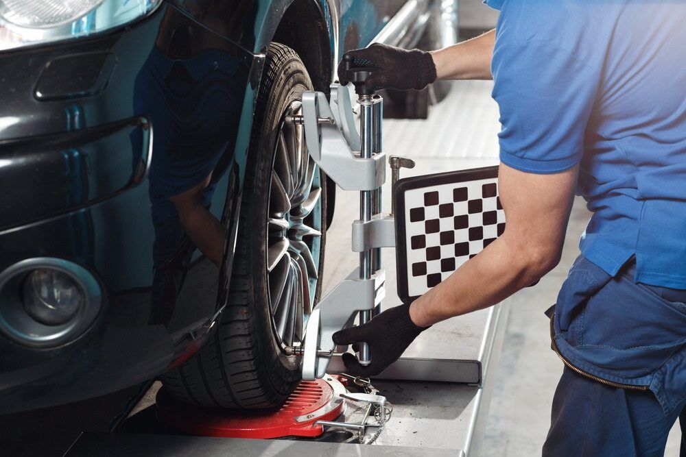 A Man is Adjusting the Alignment of a Car in a Garage — Macquarie Brake & Automotive Services In Port Macquarie, NSW