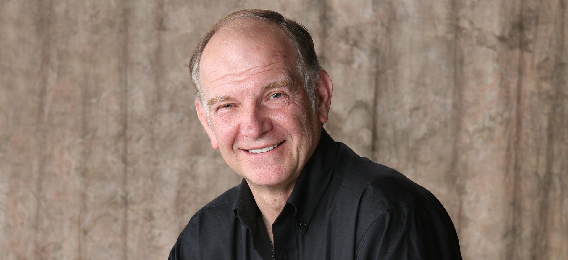 A man in a black shirt is smiling for the camera.