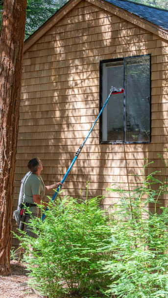 A man is cleaning a window using a window pole A man is cleaning a window using a window pole