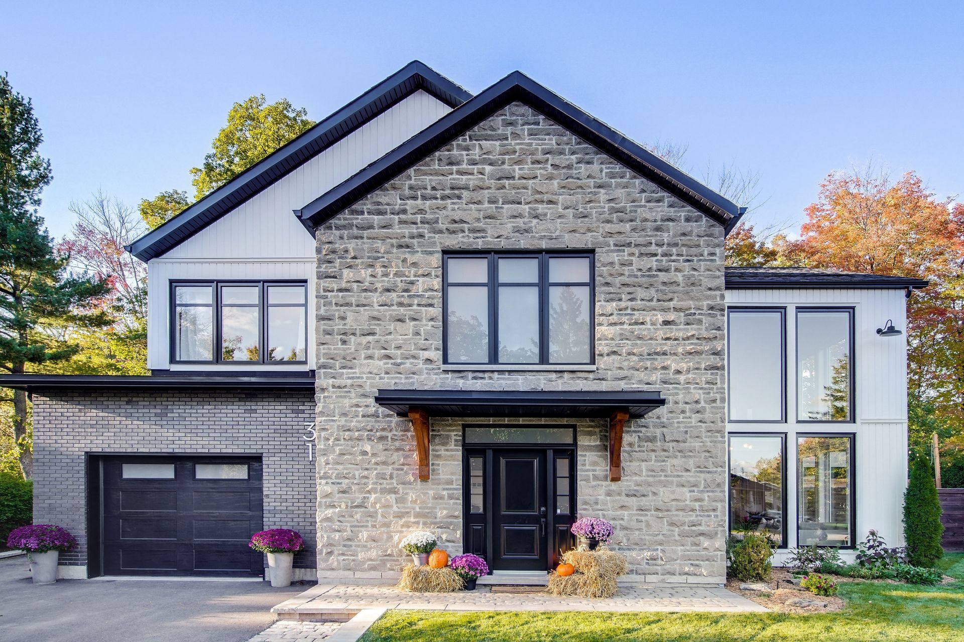 Une grande maison en briques avec des fenêtres noires et une porte de garage noire.