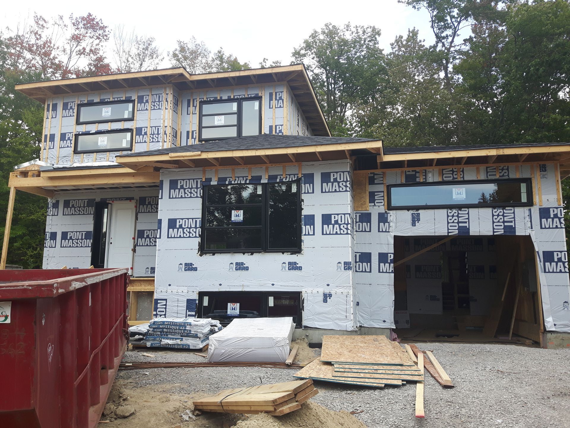 Une maison en construction avec une benne à ordures devant
