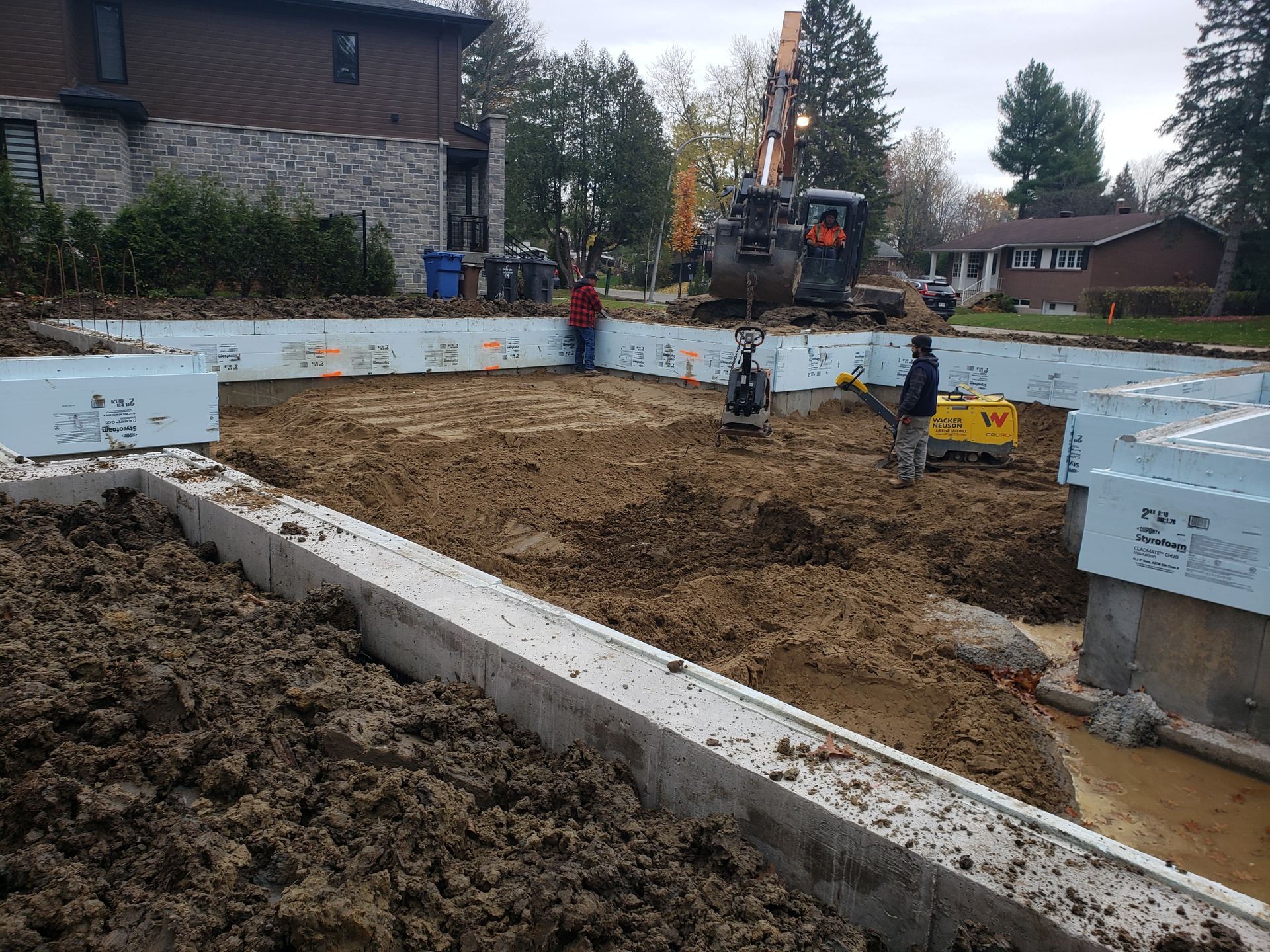 Un chantier avec beaucoup de terre et une maison en arrière-plan.