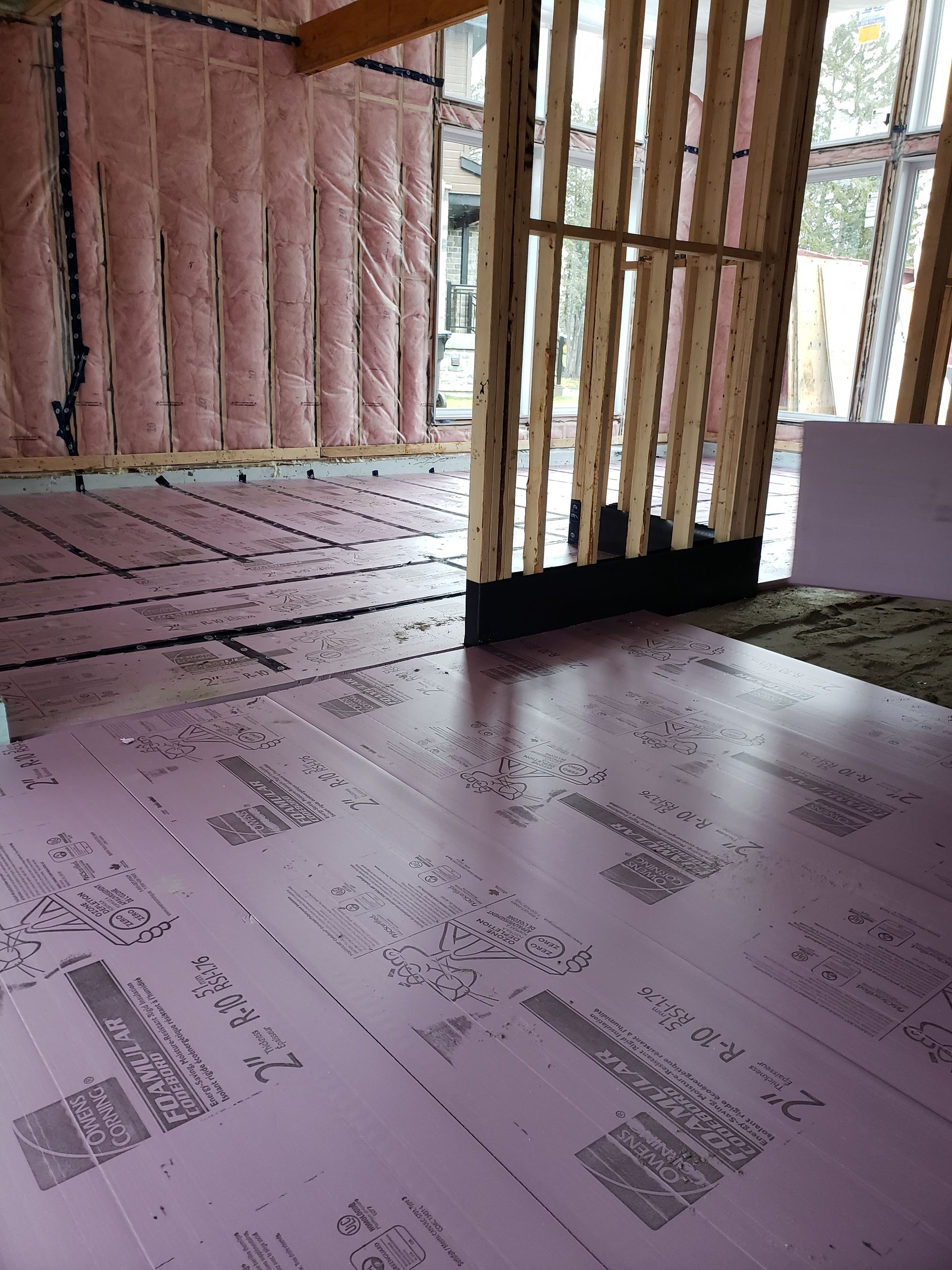 Une pièce dans une maison en construction avec une isolation rose au sol.