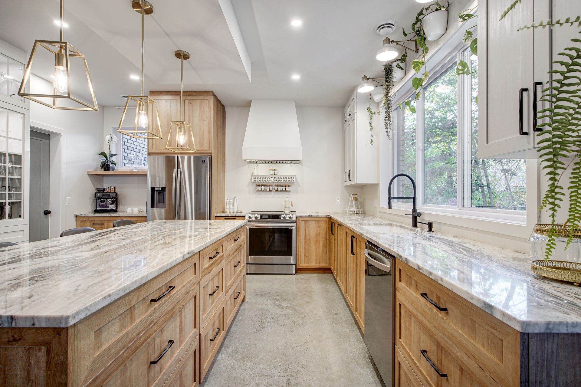 Une cuisine avec des armoires en bois, des comptoirs en granit, des appareils électroménagers en acier inoxydable et un grand îlot.