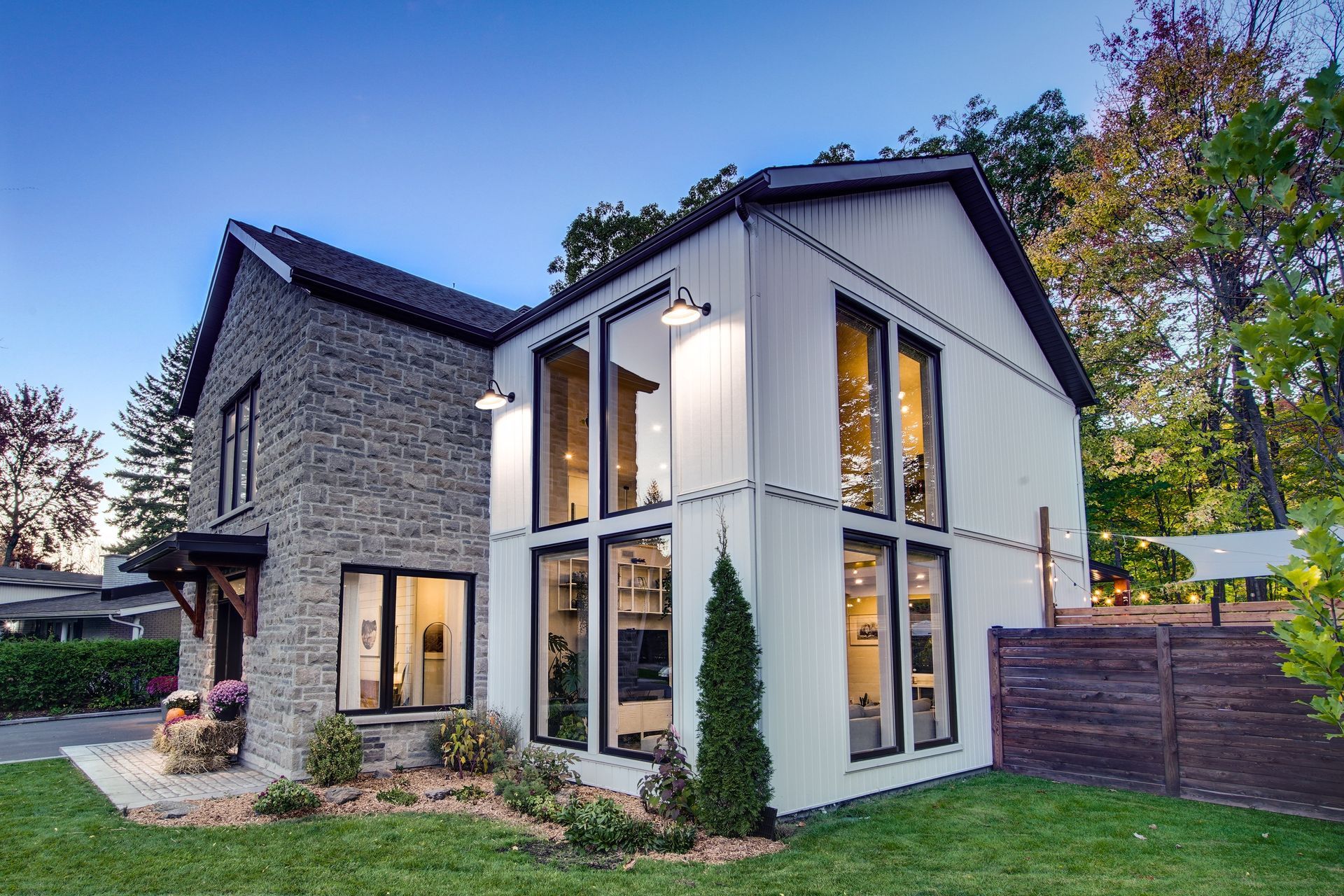 Une grande maison blanche avec beaucoup de fenêtres est située au sommet d'une pelouse verte luxuriante.