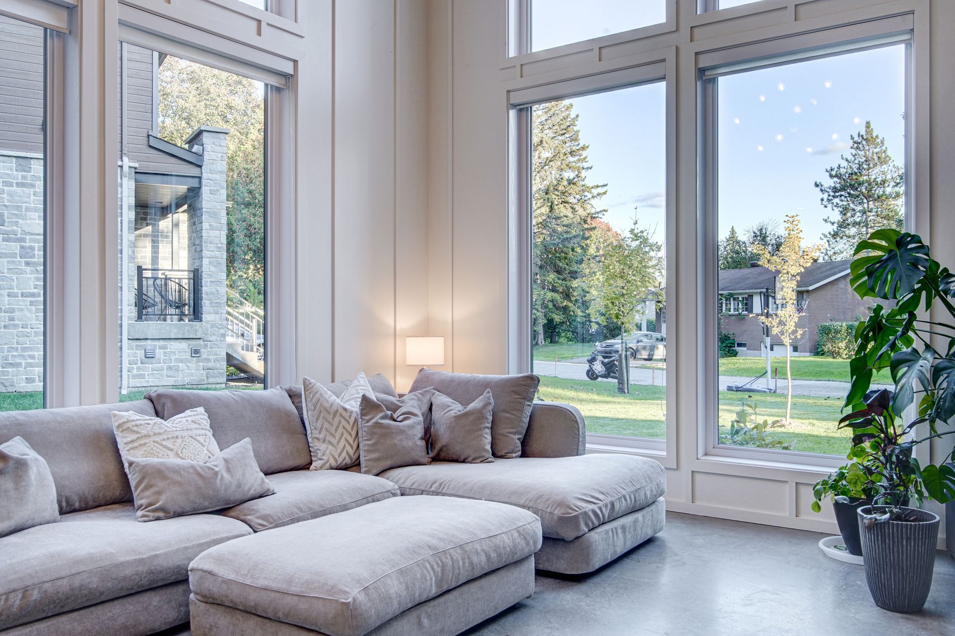 Un salon avec un canapé, un pouf et beaucoup de fenêtres.