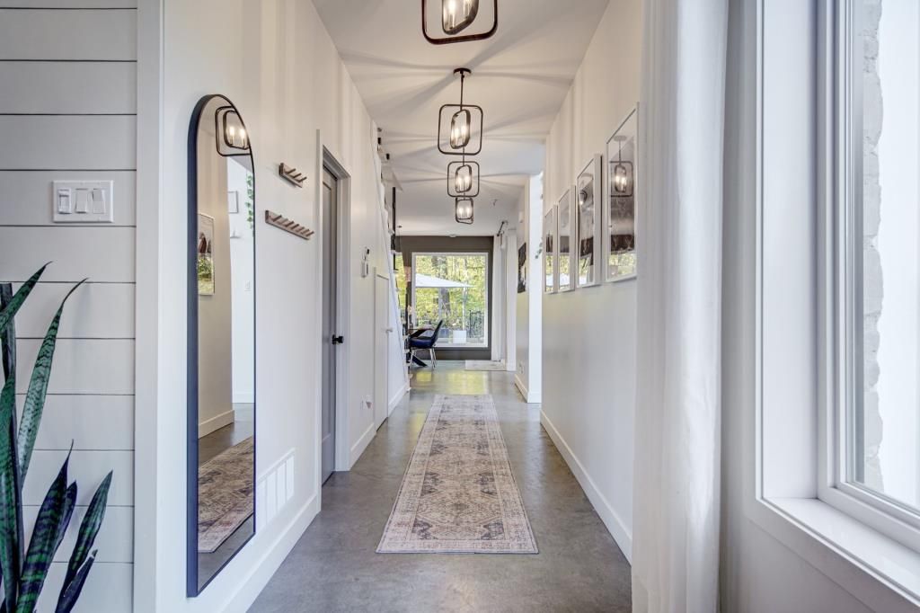 Un long couloir avec un tapis, des miroirs et une fenêtre.