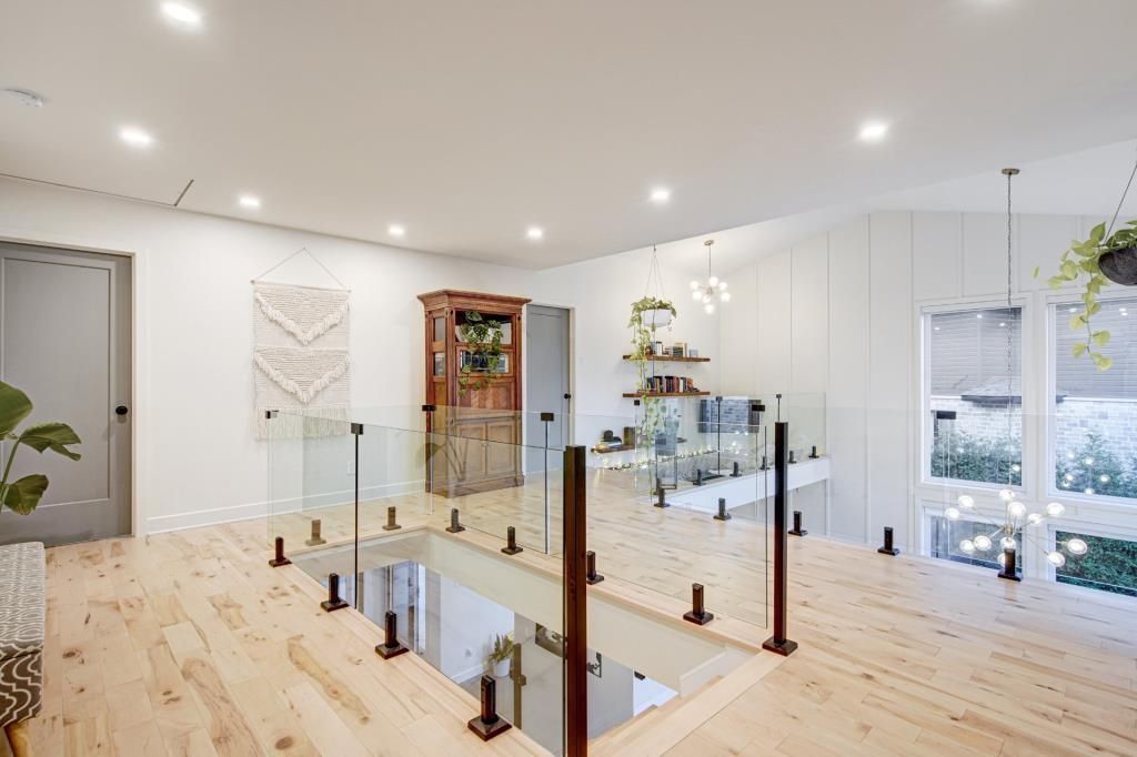 Un escalier avec une rampe en verre et un plancher en bois dans une maison.