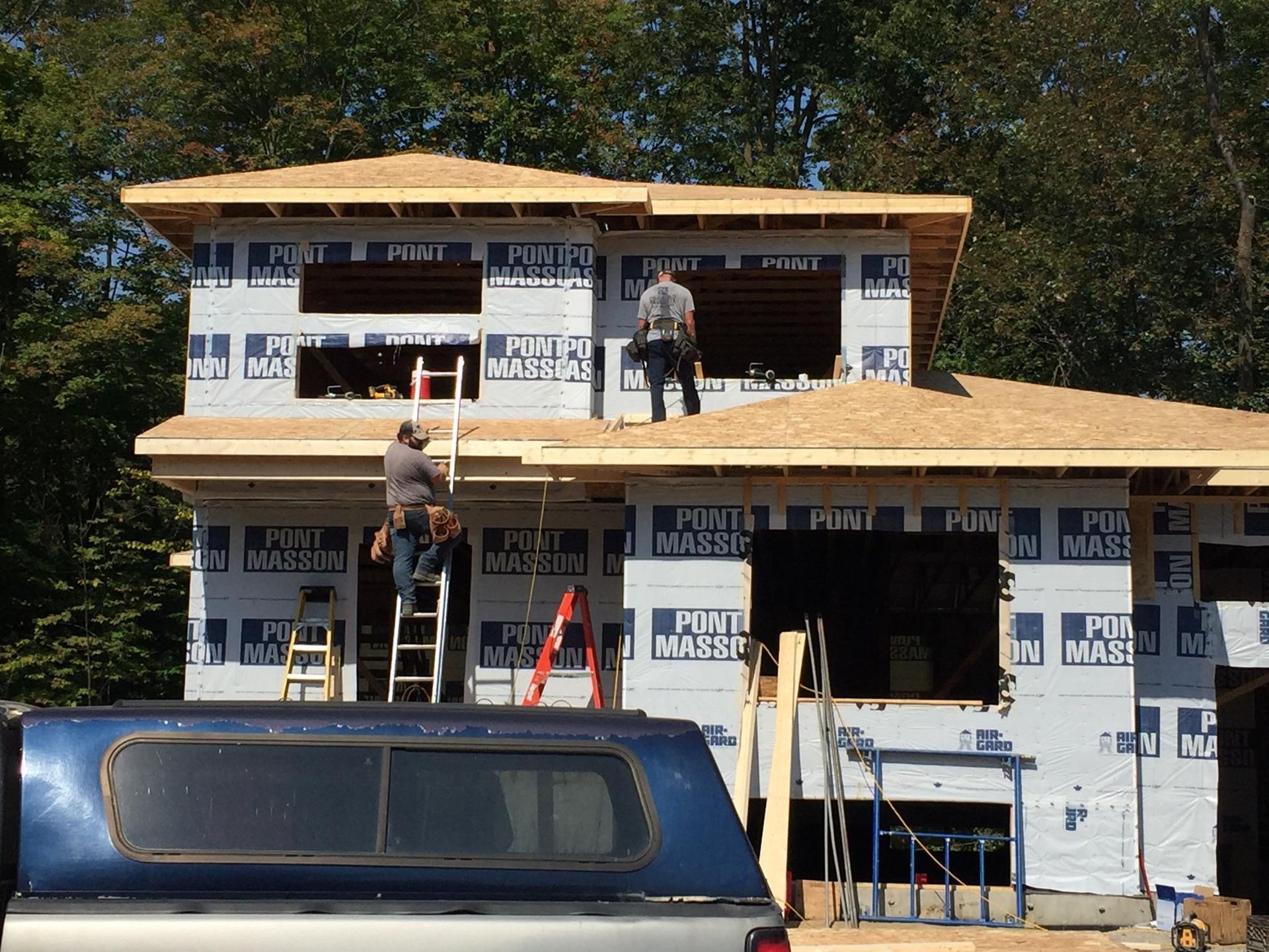 Un camion bleu est garé devant une maison en construction