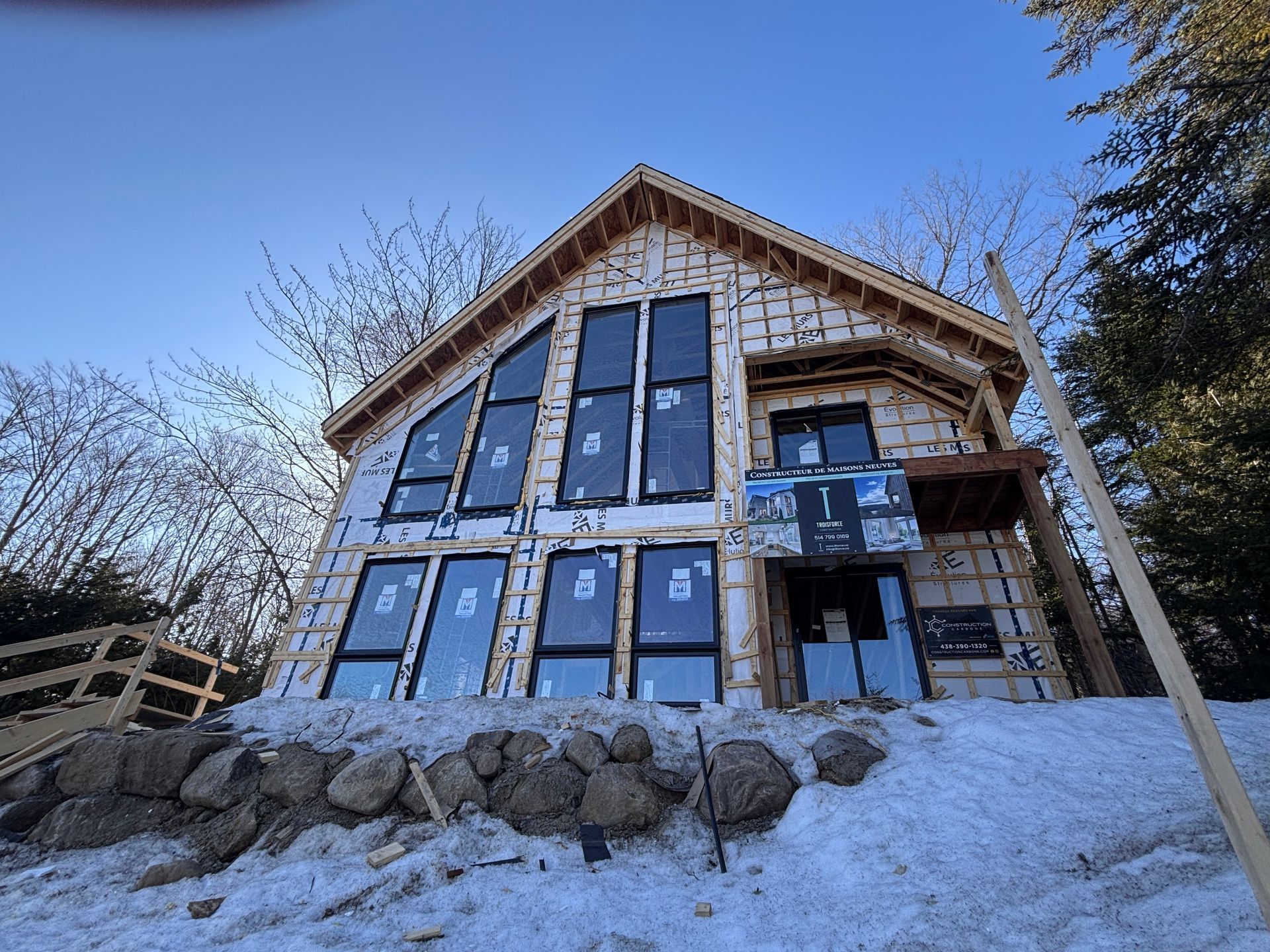 Une maison est en construction au sommet d'une colline couverte de neige.