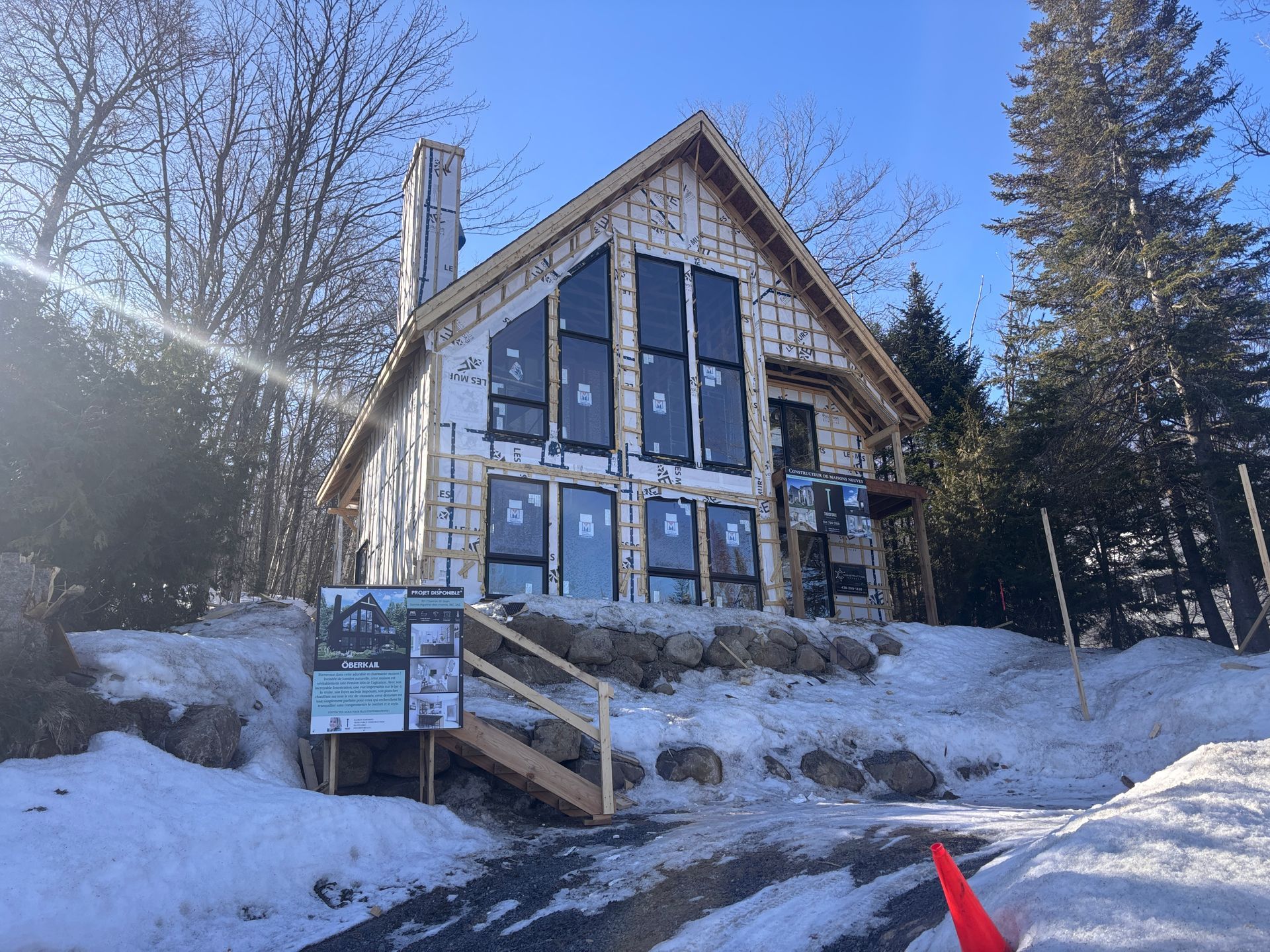 Une grande maison avec beaucoup de fenêtres est en construction dans la neige.