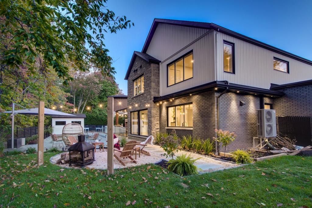 Une grande maison avec beaucoup de fenêtres est située au sommet d'une pelouse verte luxuriante.