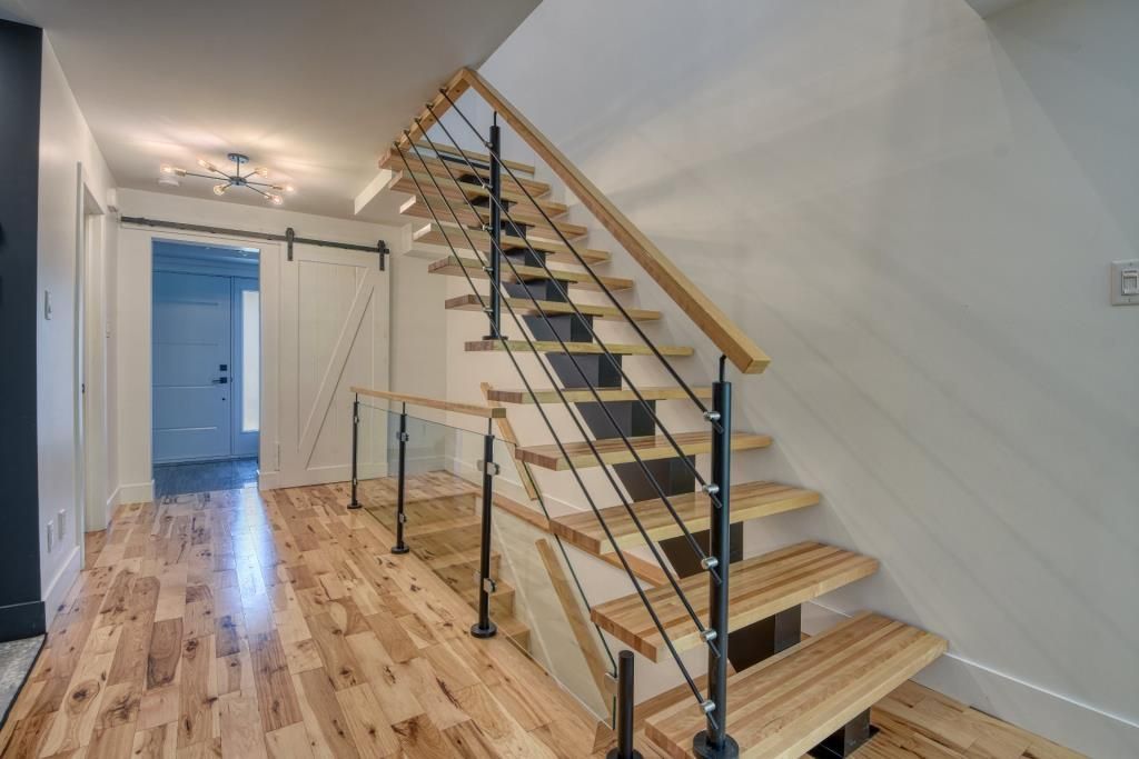 Un escalier en bois avec une rampe en métal dans un couloir.