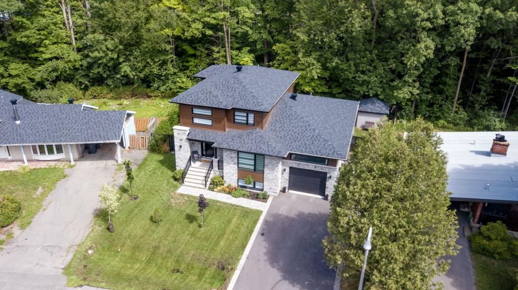 Une vue aérienne d'une maison au toit bleu entourée d'arbres.