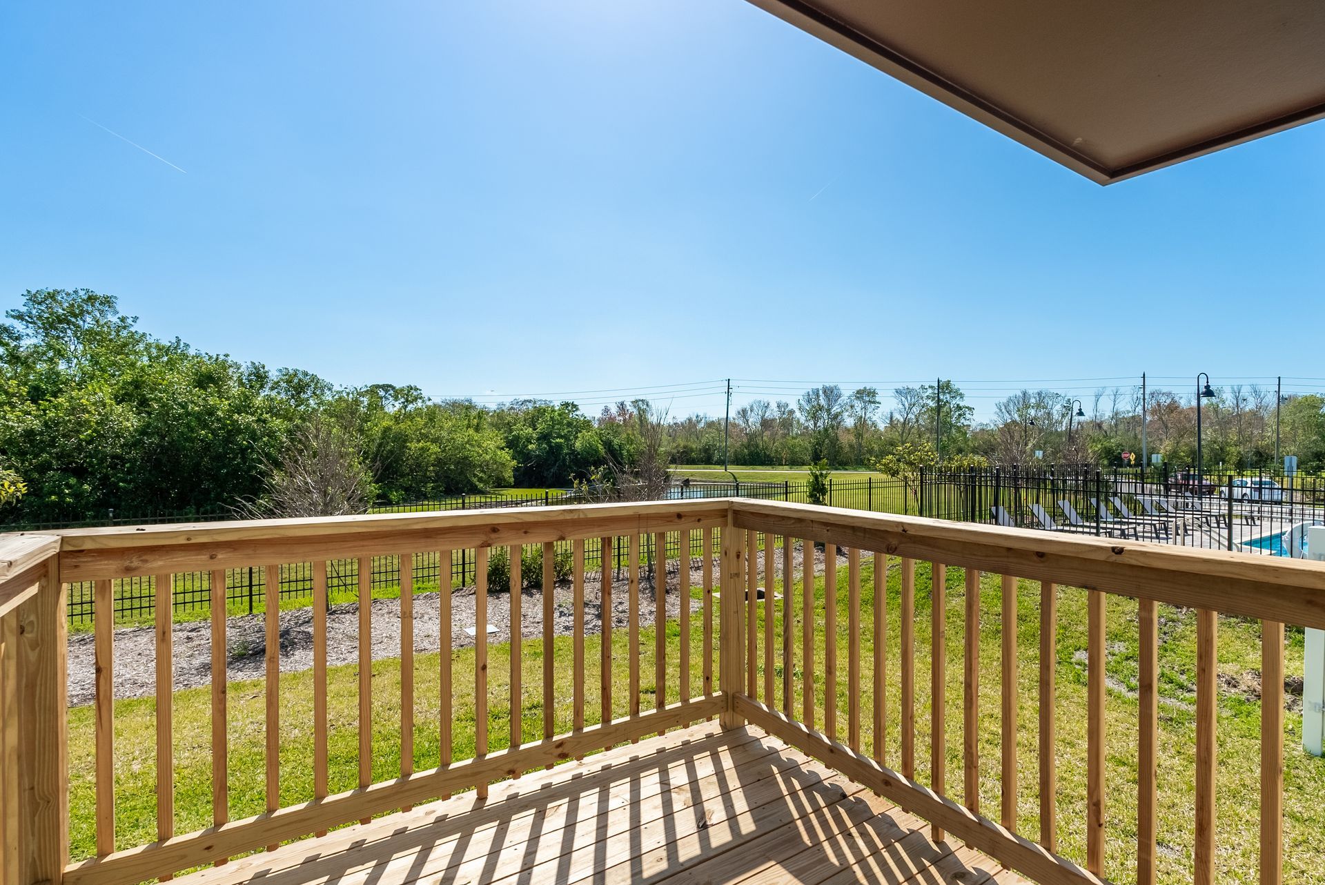 a balcony with a wooden railing overlooking a lush green field at Whitney Place Townhomes