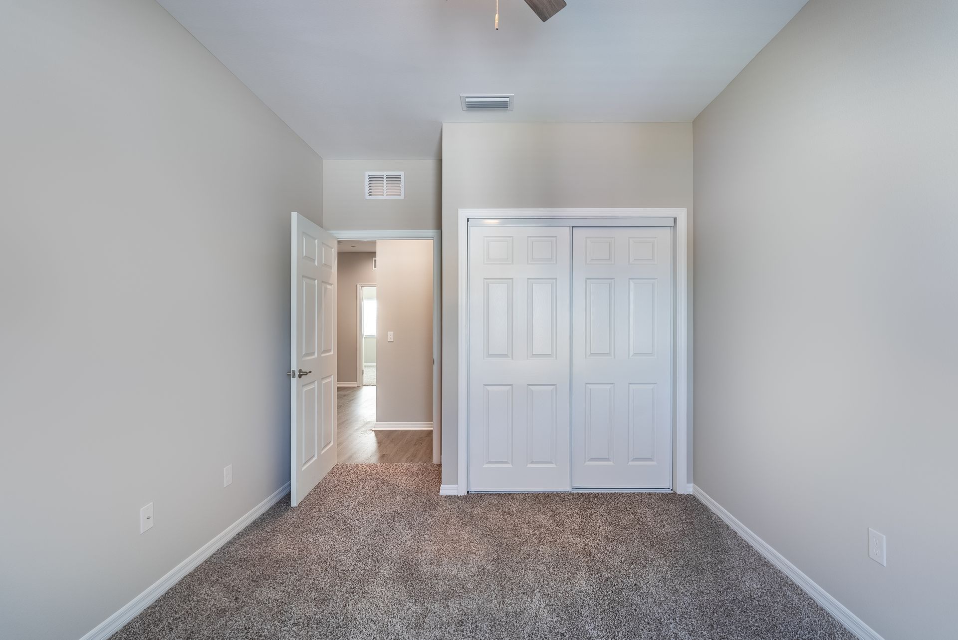an empty bedroom with a closet and a ceiling fan