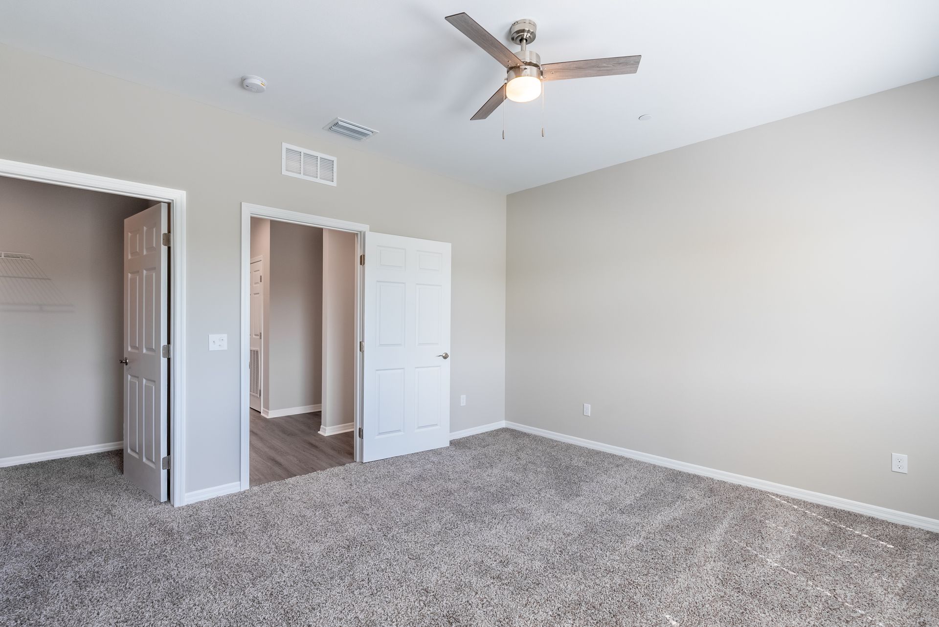 an empty bedroom with a ceiling fan and a carpeted floor