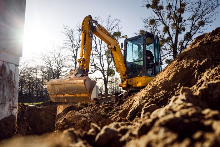 A yellow excavator is digging a hole in the ground.