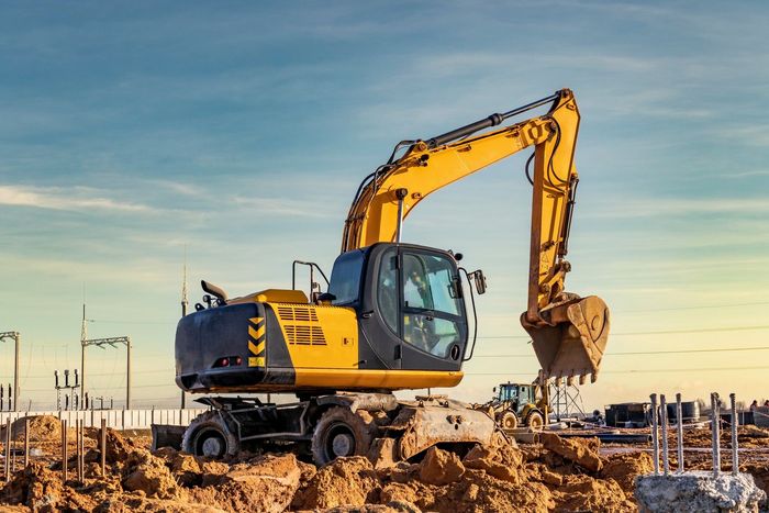 A yellow and black excavator is working on a construction site.