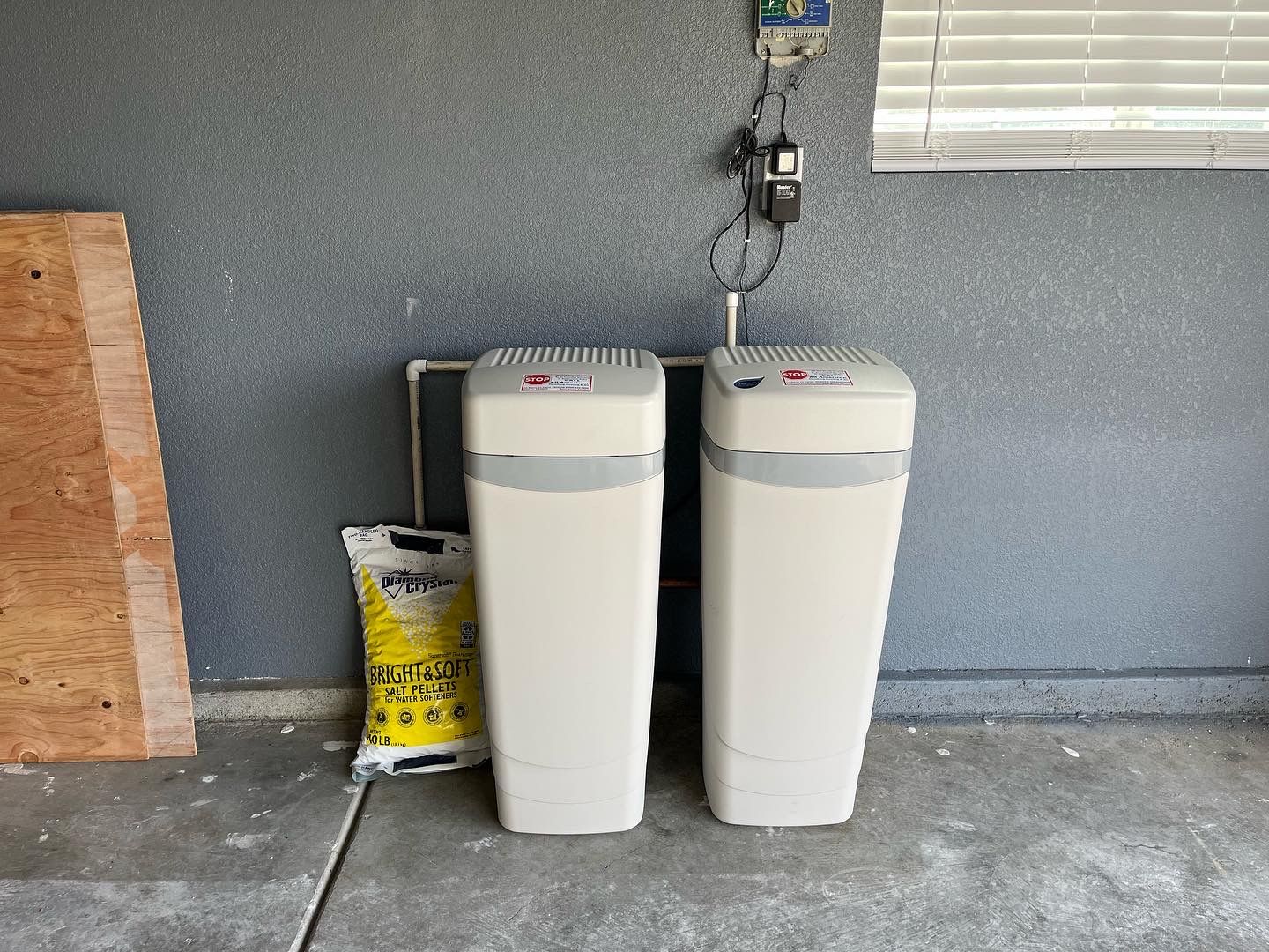 Two water heaters are sitting next to each other in a garage.