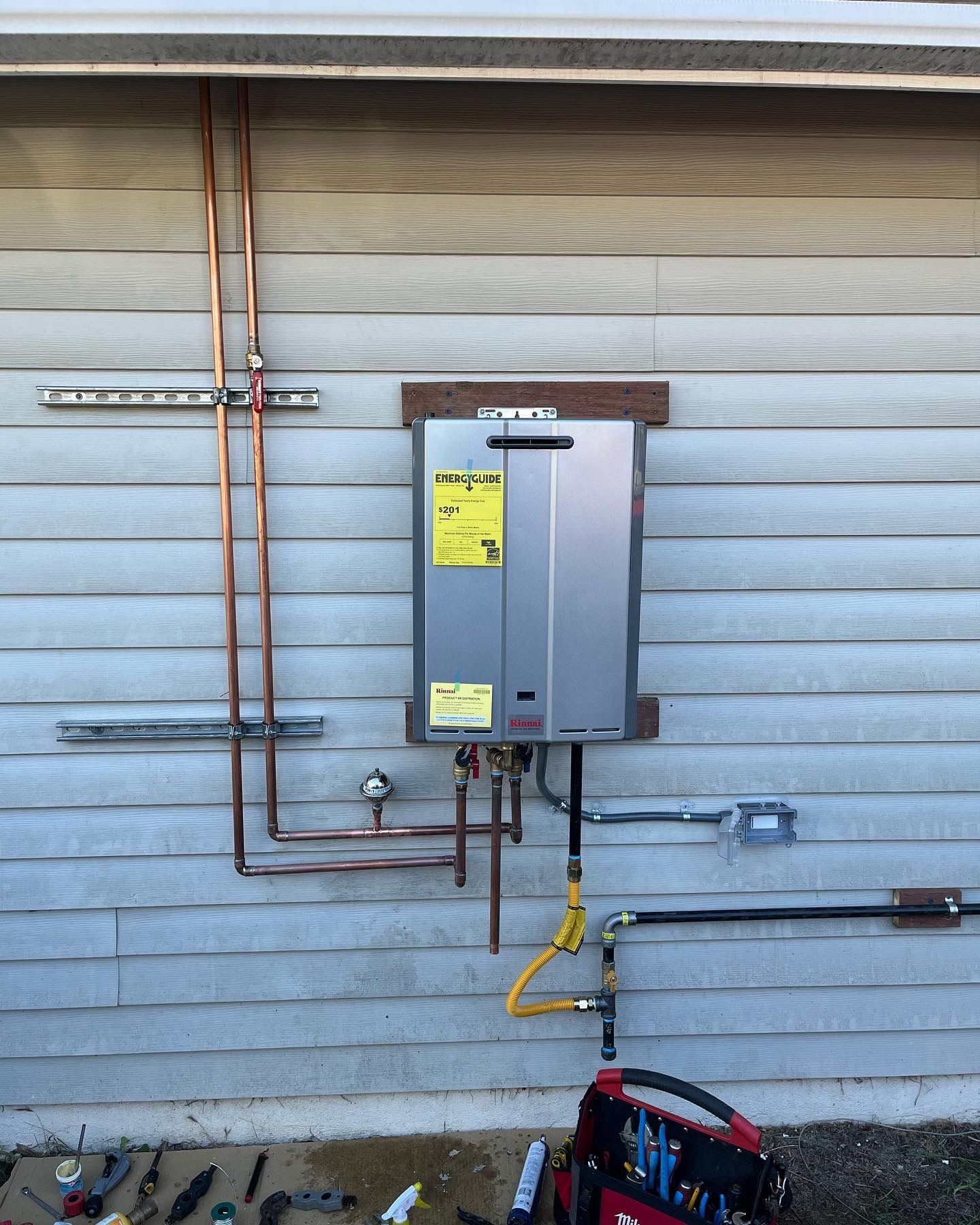 A water heater is being installed on the side of a house.