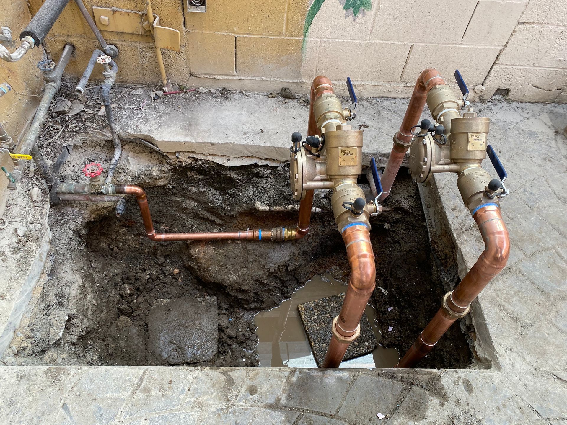 Copper pipes are being installed in a hole in the ground.