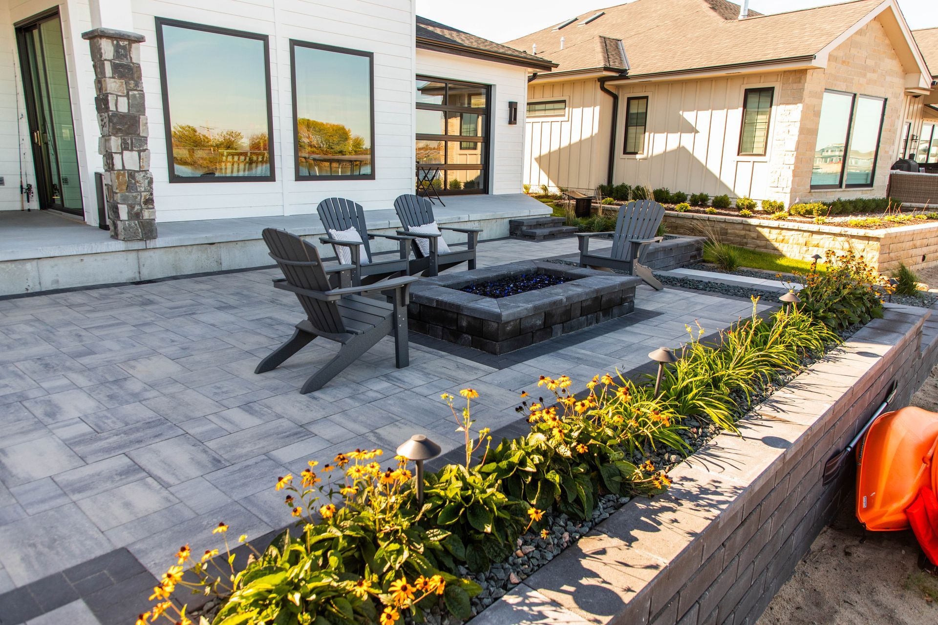 A patio with a fire pit and chairs in front of a house.