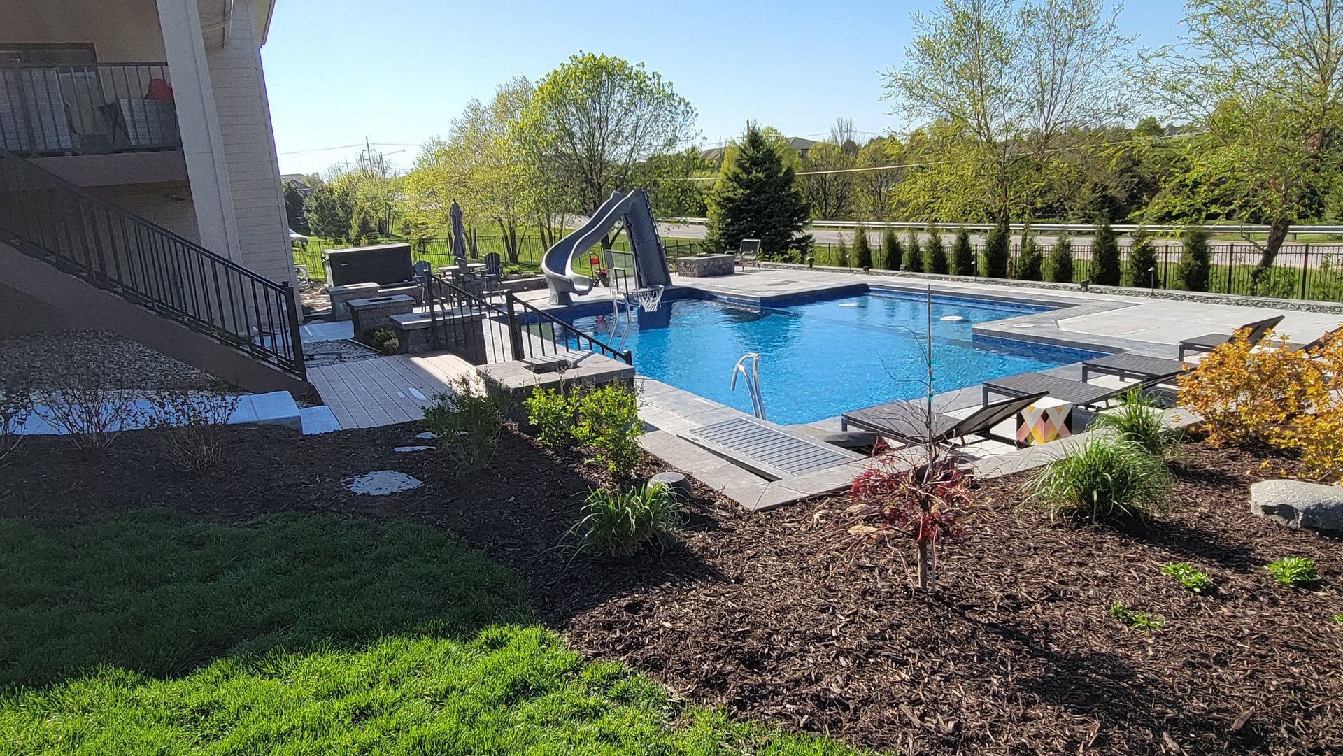 There is a large swimming pool in the backyard of a house.