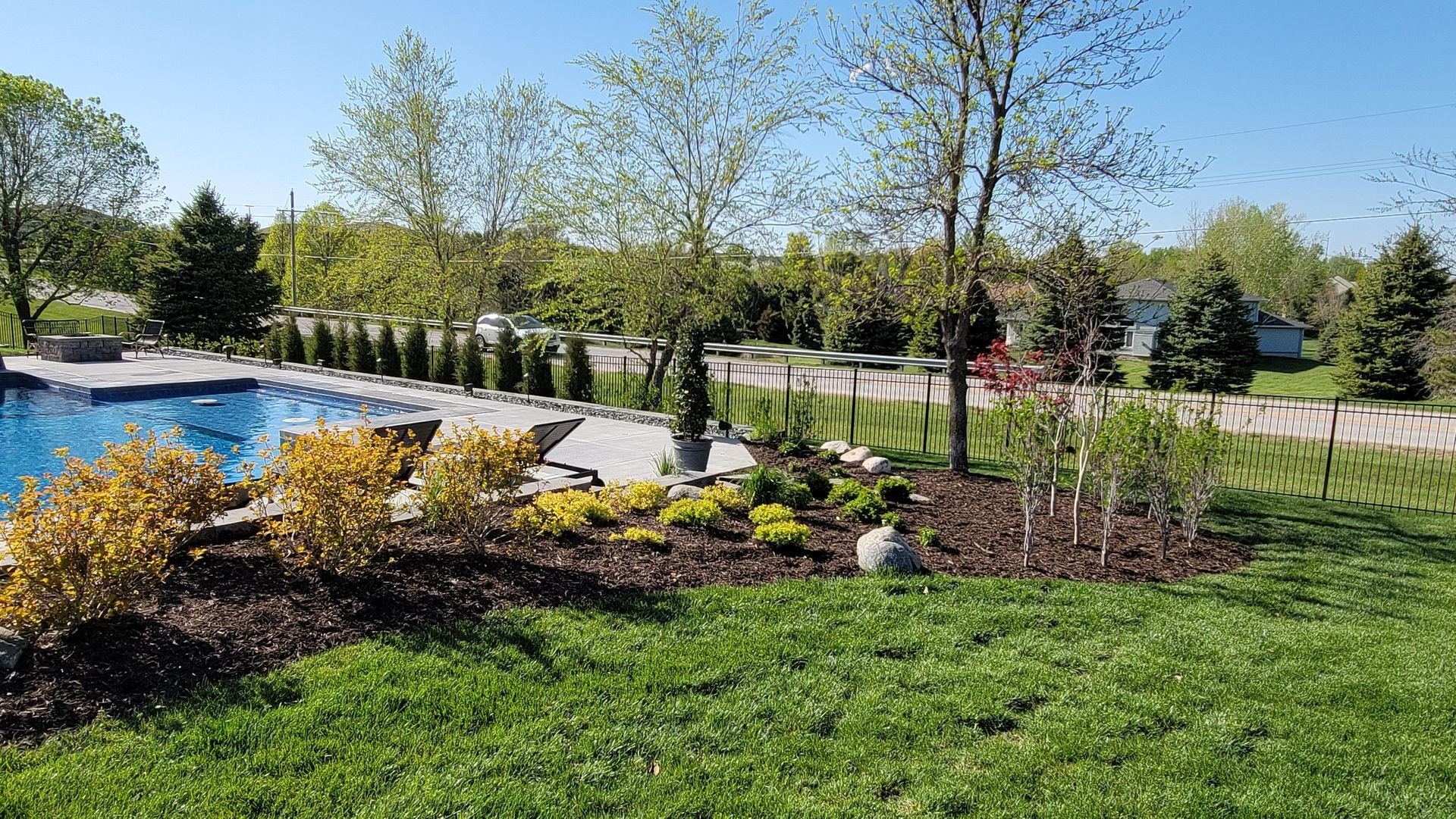 There is a large swimming pool in the middle of a lush green yard.