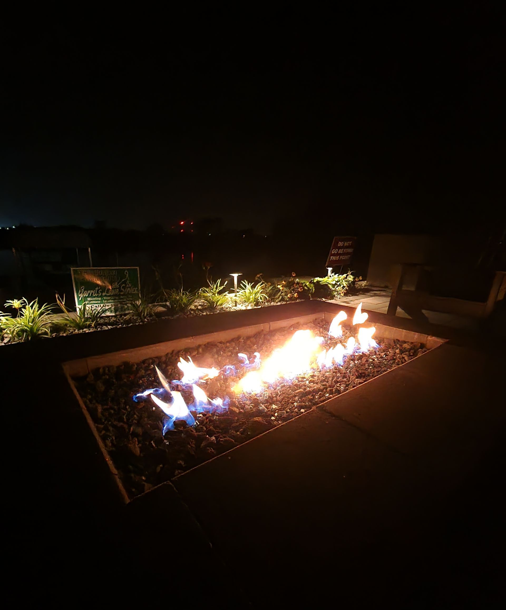 A fire pit is lit up at night on a patio.