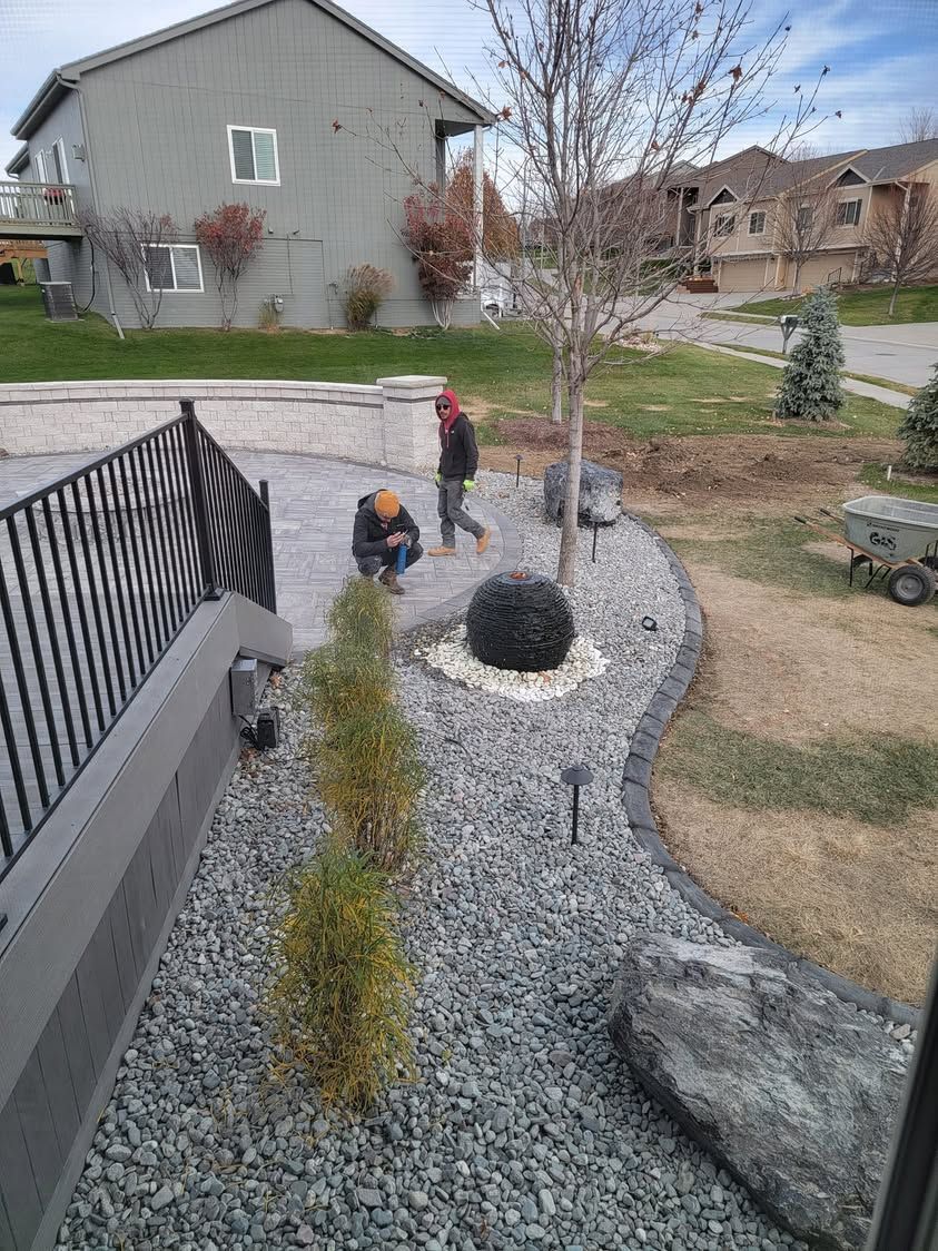 A man is kneeling down in a gravel yard in front of a house.