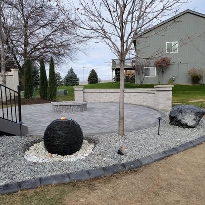 A patio with a fountain and a tree in front of a house.