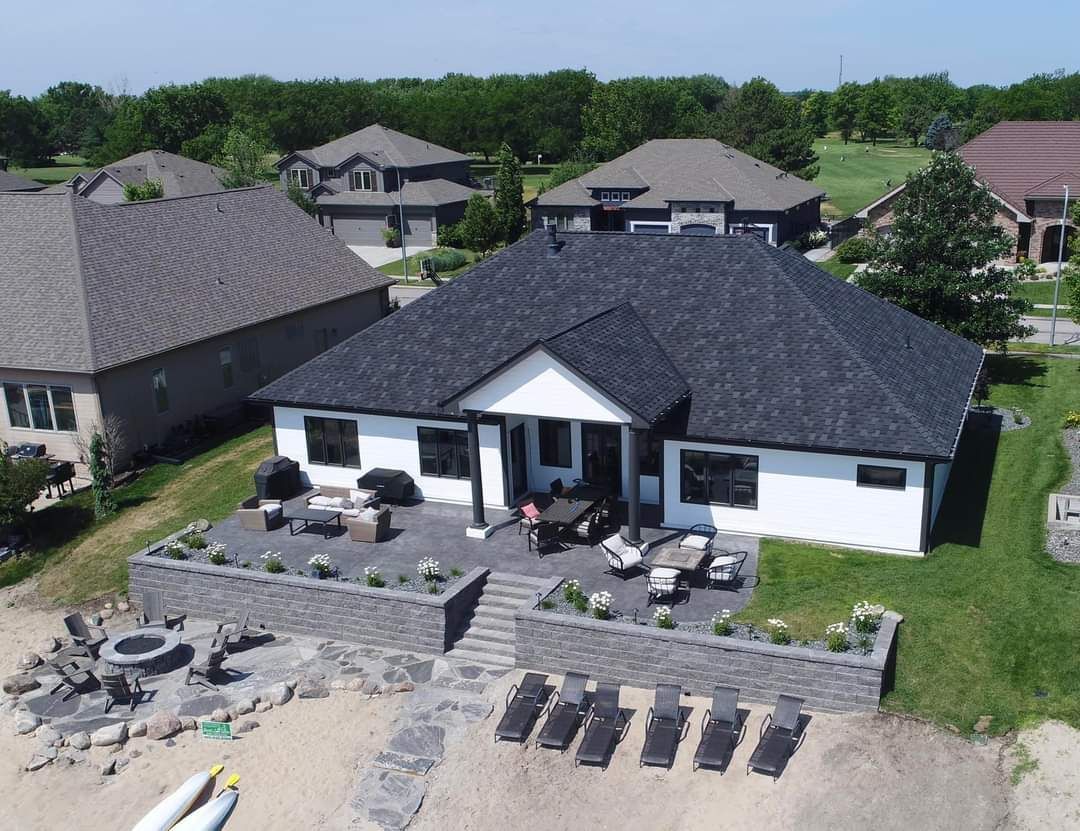 An aerial view of a house with a black roof in a residential area.