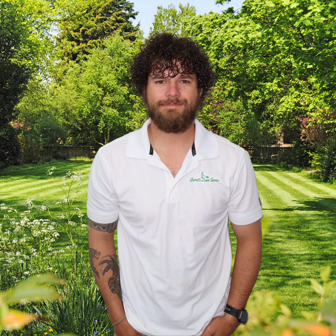 A man with curly hair and a beard is wearing a white polo shirt