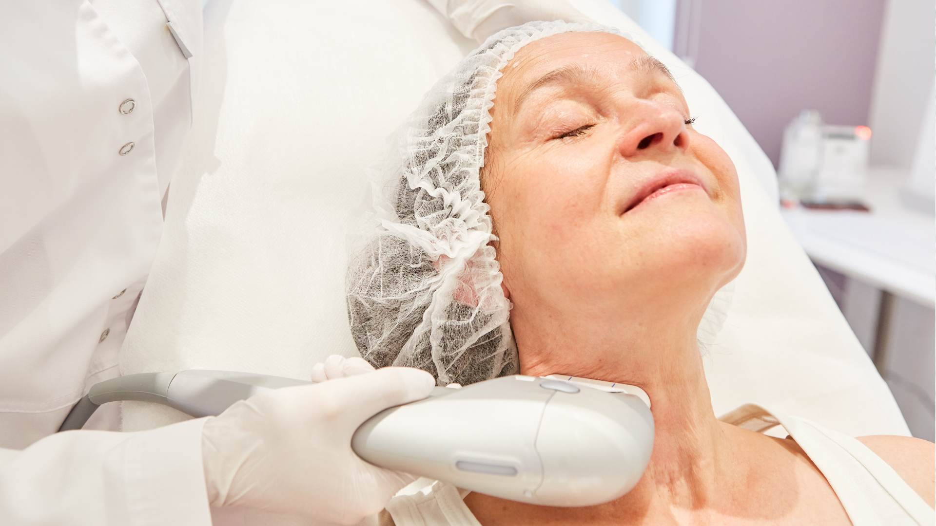 A medical professional uses a handheld ultrasound device on a person’s neck during a skin treatment procedure.