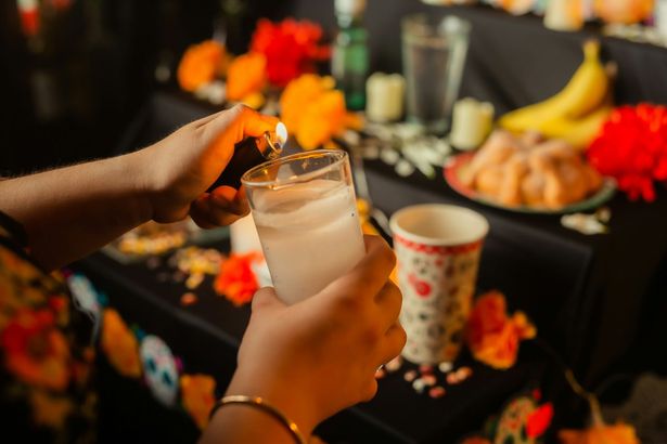 A person is lighting a candle in a glass.