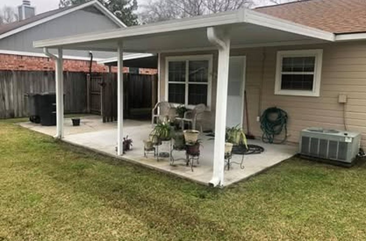 Backyard patio with a white canopy, concrete floor, and plants.