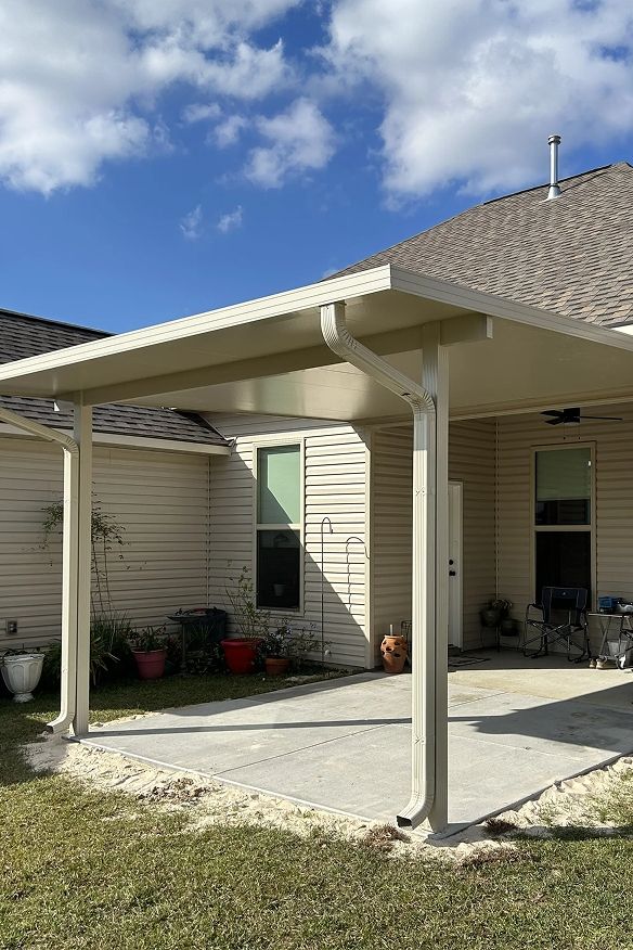 Beige patio cover attached to a house with a concrete patio and a grassy lawn.