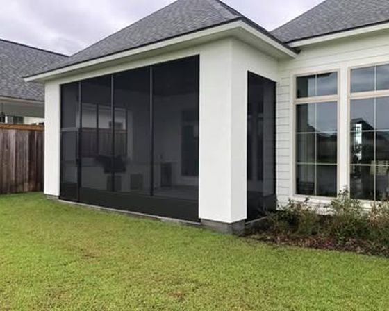 Screened-in porch attached to a white house with a dark roof and grass lawn.