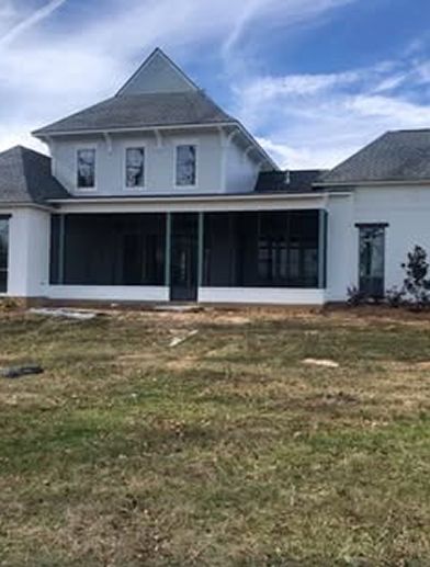 White house with gray roof and screened porch; grassy yard, partly cloudy sky.