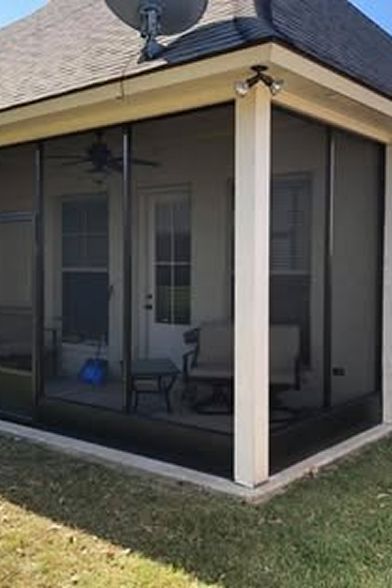 Screened-in porch with light-colored posts and dark screening. Interior with chairs and doorway visible.