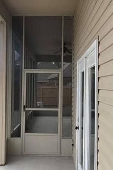 Screened-in porch with a screen door and adjacent French doors on a beige house.